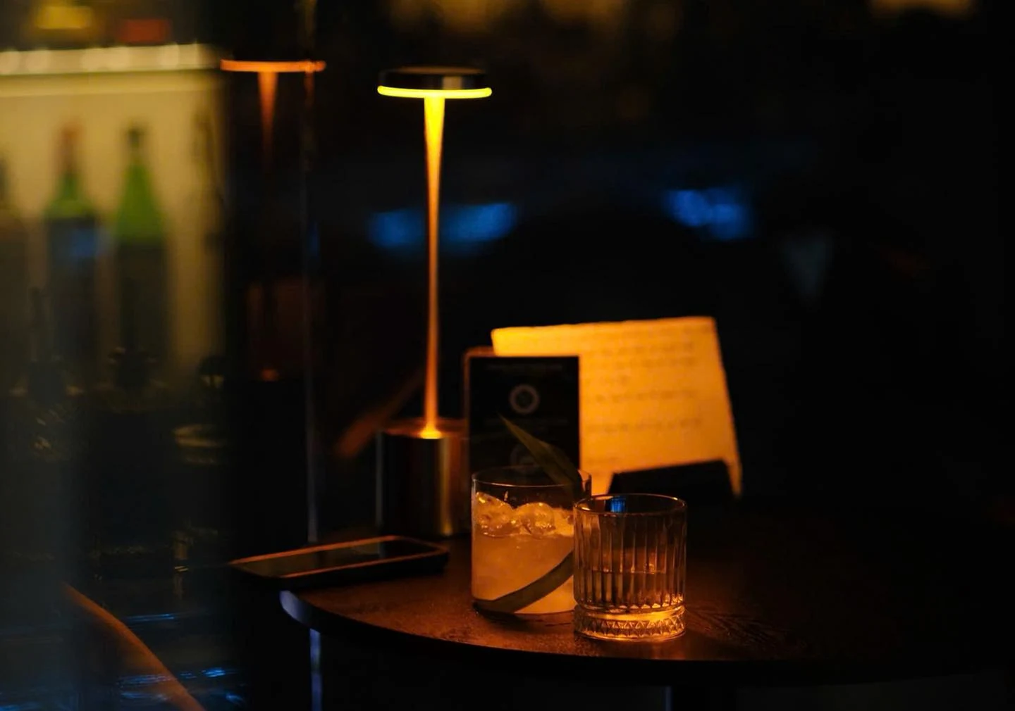 Two drinks under a warm table lamp